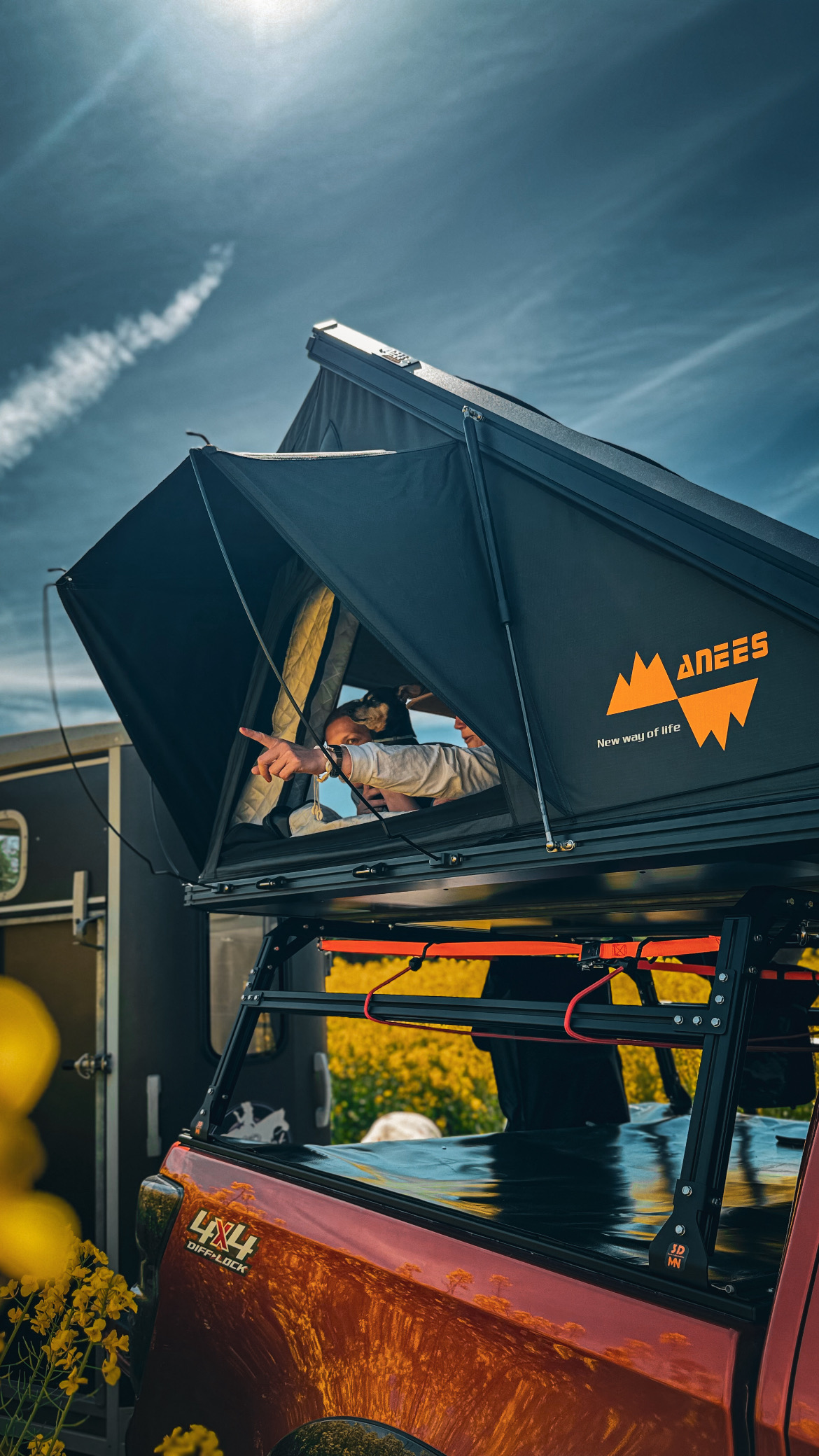 Pferd blickt aus dem Stall, daneben Auto mit aufgebautem Dachzelt auf dem Hof